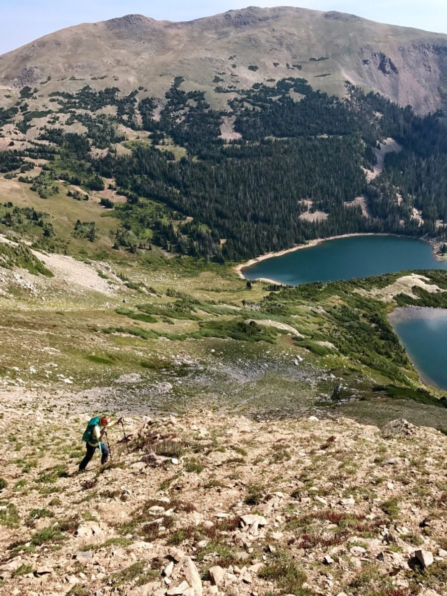 Emily Sehloff backpacking up a climb toward the ridge with Hang Lake, Blue Lake, and Cameron Peak in the background. Photo by Ryan Bettin.