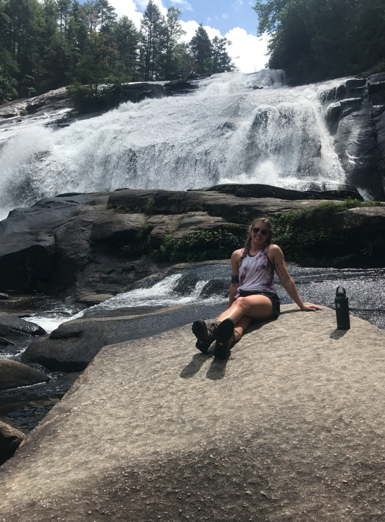 Writer Kaelin Stallsworth sitting on rocks in front of a waterfall in Brevard ,NC.
